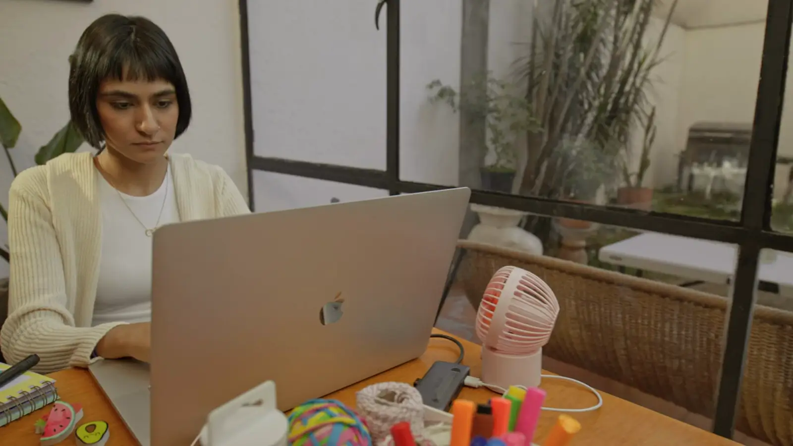 A woman working on a laptop at a table by a window